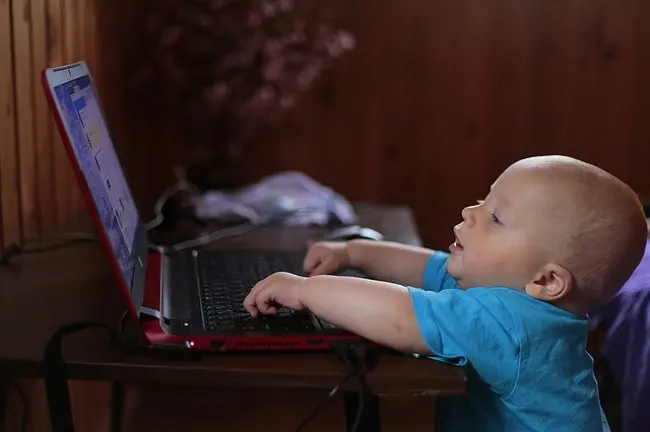 bambino piccolo curiooso davanti ad un pc