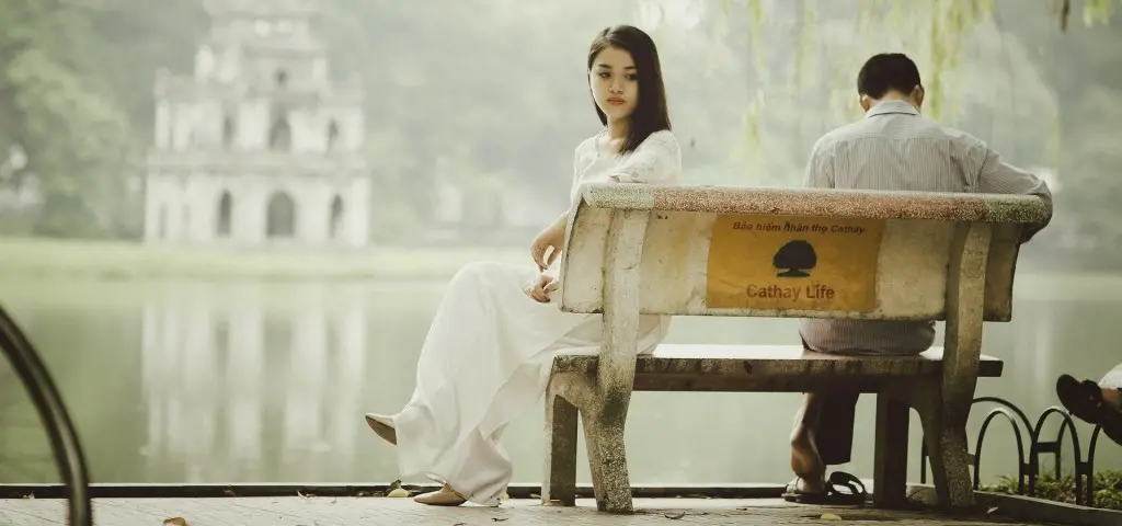 una coppia in giovane età seduta su una panchina in riva al lago