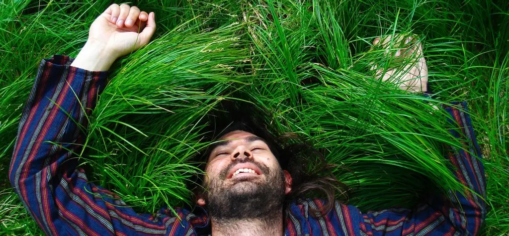 Ragazzo felice disteso su un prato, stato d'animo tipico della psicologia positiva